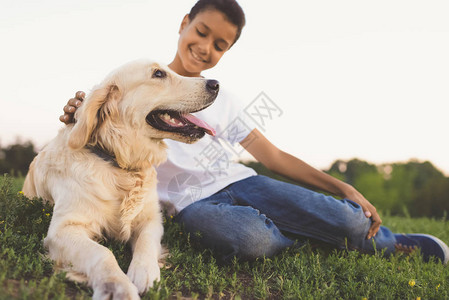 可爱的猎犬和快乐的非洲青少年坐在草地图片