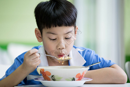 坐在家里吃饭的年轻亚裔男孩图片