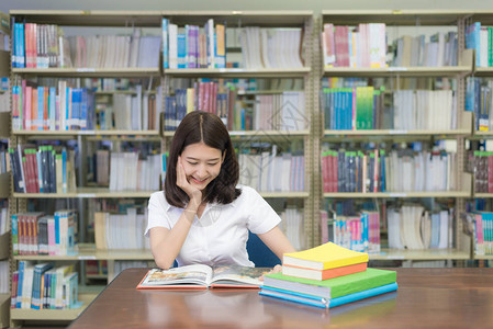 大学图书馆的亚裔学生阅读书校对P图片