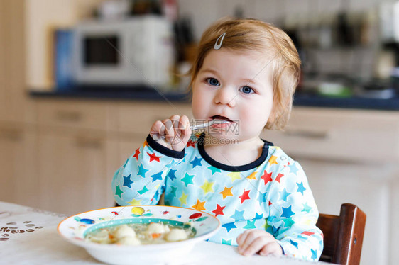 可爱的女婴从勺子蔬菜面条汤吃食物儿童喂养和发展理念可爱的蹒跚学步的女儿图片