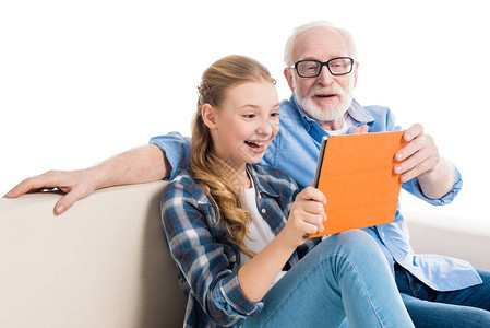 祖父和孙子使用数字平板电脑坐在沙发上图片