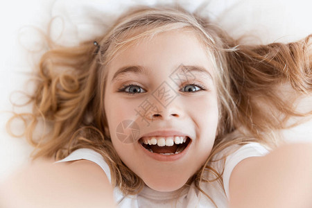 坐在床上看镜头的笑可爱孩子的风景背景图片