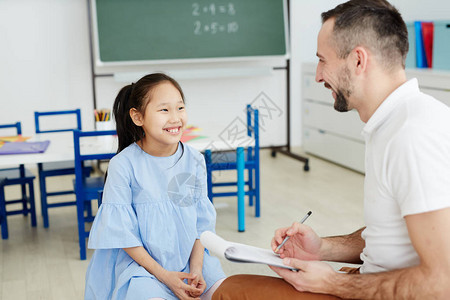 快乐的女学生看着她的老师在个别课中听图片