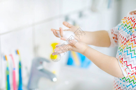 蹒跚学步的小女孩在浴室里用肥皂和水洗手的特写镜头关闭孩子学习清洁身体部位早上的卫生习惯健康的孩子在图片