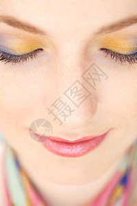 近距离的美容肖像一个年轻女脸穿着蓝色和黄色化妆品她的眼睛闭图片