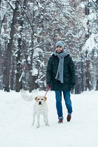 青年男子与狗在冬季公园带皮图片