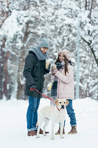 在白雪皑的公园里快乐的夫妇带着咖啡去图片