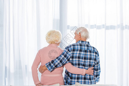 美丽的老年夫妇在窗前拥抱图片