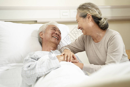 探望和与住院丈夫在床边交谈的年长有爱心和关图片