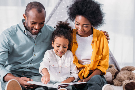 快乐的非裔美国女儿为父母在家读书图片