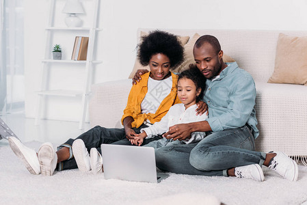 非洲父母和女儿在家看笔记本电脑的电影图片
