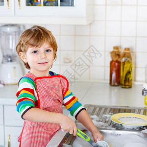 有趣的小男孩在家庭厨房里帮助和洗碗孩子很开心帮助他的父母做家务在室内图片
