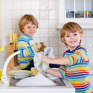 有趣的双胞胎男孩在厨房帮忙洗碗孩子们在做家务时很开心室内图片