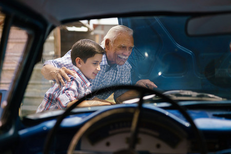 家庭和代沟老爷和孙子在一起这位老人展示了一辆从60年代到十几岁的孩子的老爷车的引擎他们笑得很开心图片