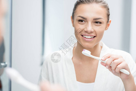 快乐女人早上刷牙时照镜子的肖像图片