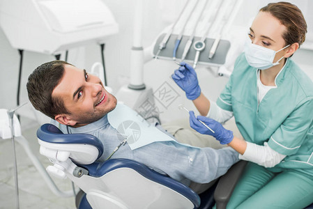 口腔医生用假牙在牙科诊所的快乐病人附近图片