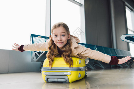 兴奋的青春期前孩子躺在行李箱上在机场候图片