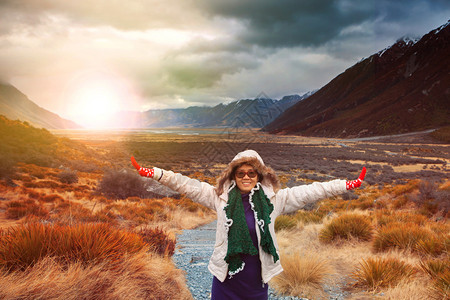 身穿冬衣的女旅行者在太阳升起的自然山景中拍摄一张带有幸图片
