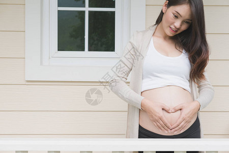 怀孕产期孕妇在家庭门口的肚子上做心脏形状标记图片
