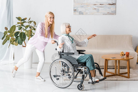 在养老院与快乐的老年妇女一起推轮椅的图片