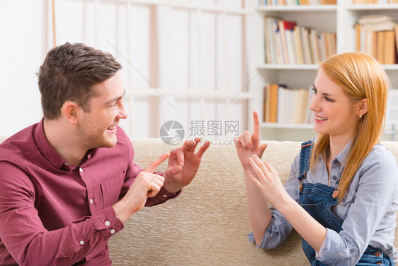 微笑的年轻女子与听力障碍男子使用手语说话图片