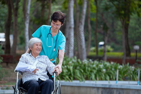微笑的护理人员高级护士照顾坐在轮椅上的高级病人放图片