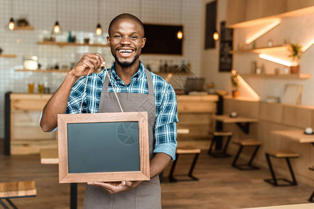 微笑的非洲裔美国咖啡店男老板拿着木框图片