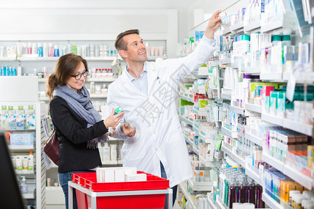 为药店女顾客摘除药品的实验室服中微笑图片