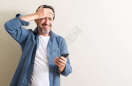 使用智能手机的老人用手在头上压力很大图片