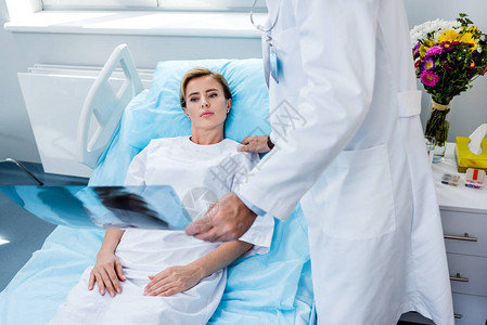 男医生持有X光照片和在医院室为女病人欢欣鼓舞的画图片