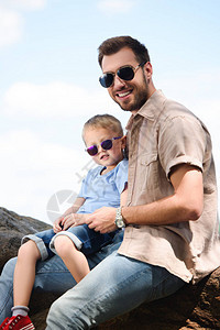 快乐的父亲和儿子在太阳镜中看着图片