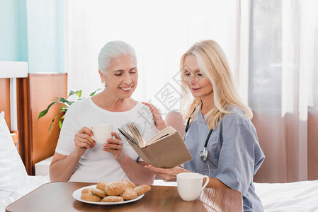 微笑的高级妇女和护士在医院看书图片