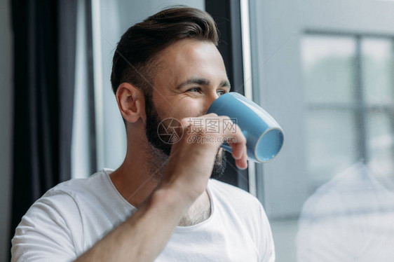 英俊的年轻男子喝茶从杯子喝茶图片