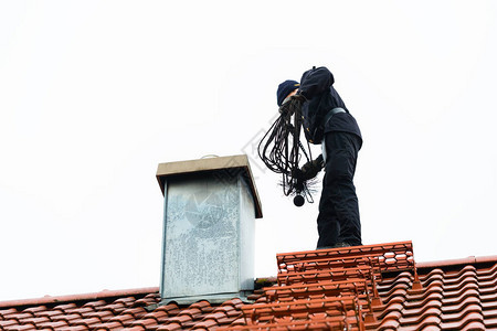 烟囱清扫站在家庭工作的屋顶上图片