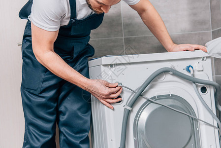 在浴室内修理洗衣机的男杂图片