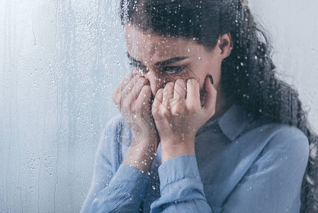 压抑的女人用双手蒙住脸用雨滴背景图片