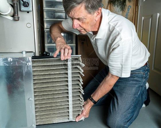 在地下室的HVAC锅炉系统中更换一个折叠脏空气过滤器的高图片