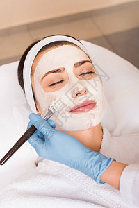 美容师在美容院当面用化妆面具对脸部妇女图片