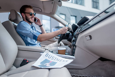 青年男子在驾驶汽车时用智能手机说话图片