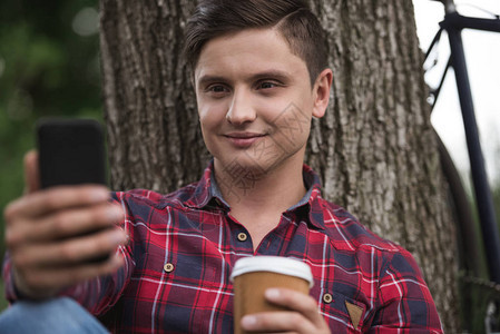 笑的男人喝咖啡和用智能手背景图片