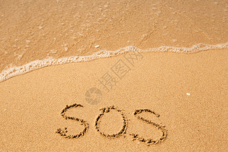 SOS写在沙滩纹理上的沙子上图片