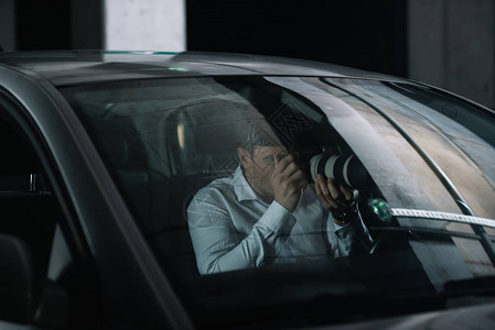 男私家侦探用相机监视器监控他的车上有背景图片
