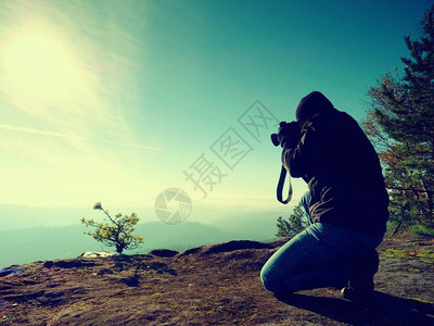 摄影师往下看迷茫的山谷男人跪在悬崖上拍照梦幻般的顽固景观图片