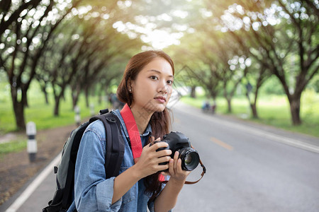 女摄影师在野外拿着摄像头拍摄旅游者的照片图片