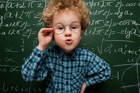 聪明的孩子触摸眼镜手站在黑板图片