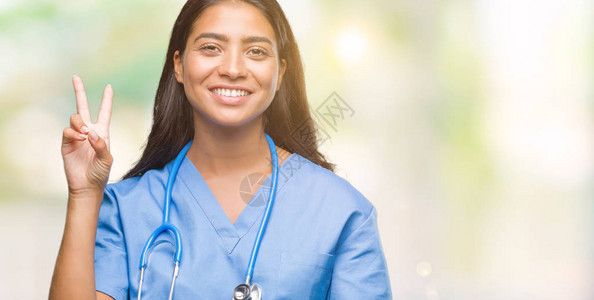 年轻的阿拉伯医生外科医生女人在孤立的背景下展示并用第二号手指向上方图片
