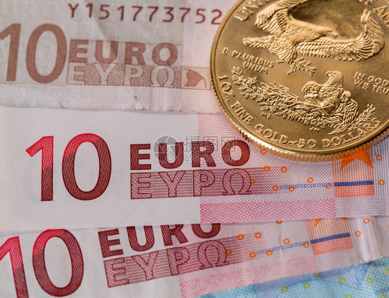 实金硬币与欧元钞票上的数字形成对比表明图片