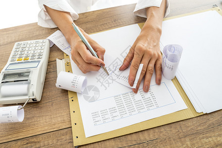 会计师或财务顾问在制作最终报告时检查和比较收据和统计数据图片
