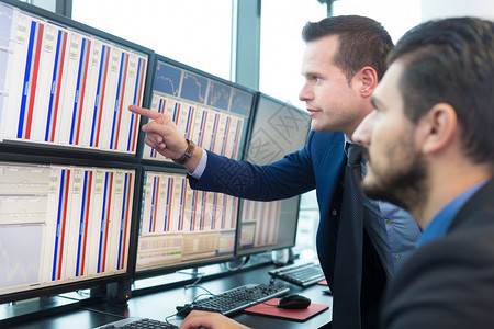 买卖股票的商人股票交易员在多个电脑屏幕上查看图表指数和字同事们在交易图片