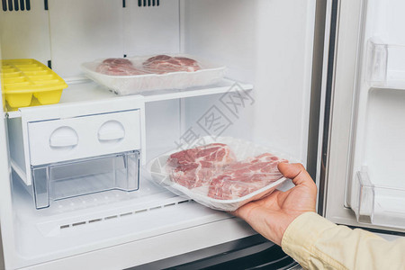 男人从冰箱里取出冷冻肉的剪影图片